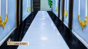 A hallway with a black and white floor, gold accents on the walls, and a green plant in the center. - De Lords Resort Hotel & Suites (Lagos)