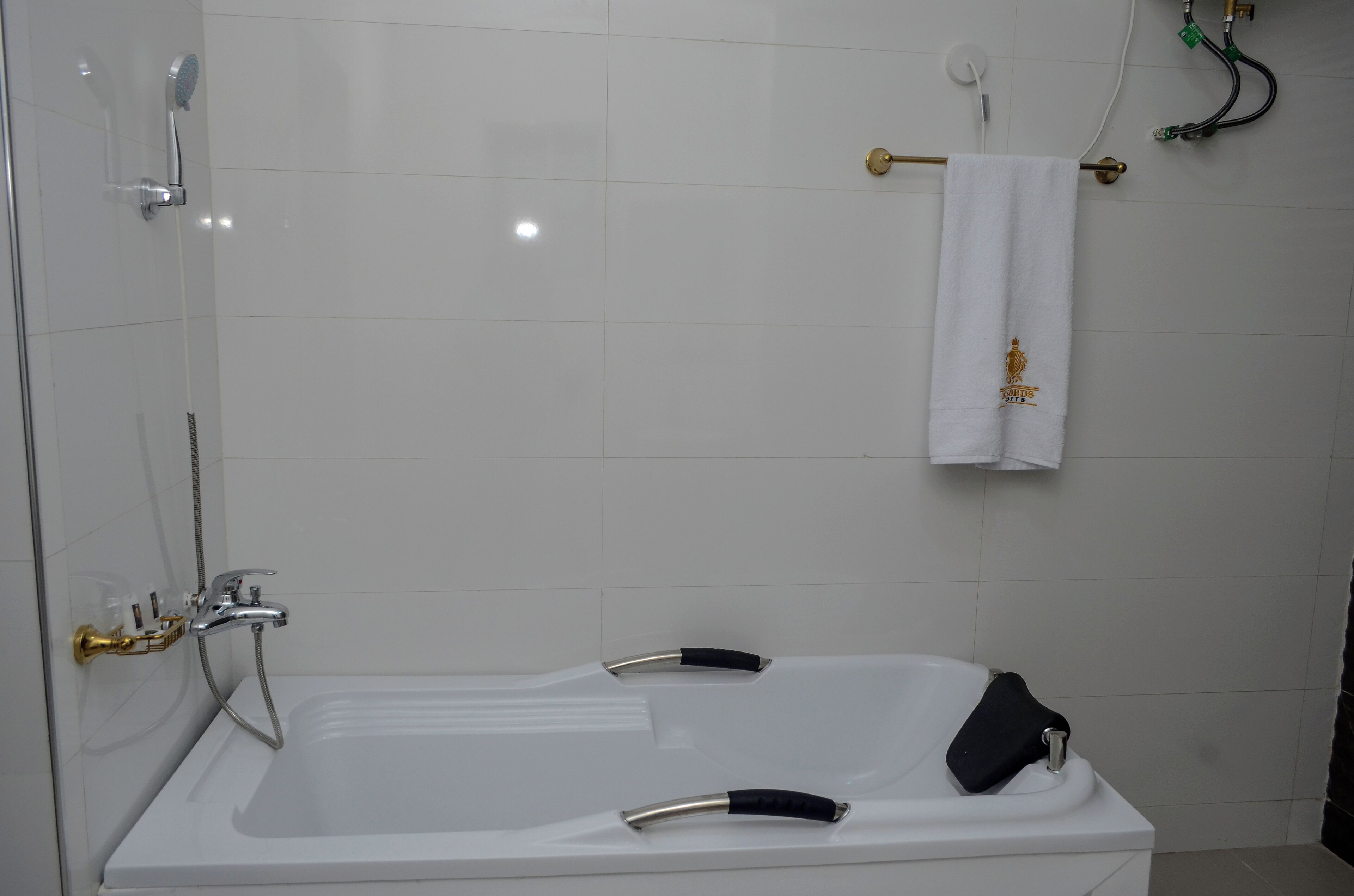 A modern bathroom with a white bathtub, a shower area, and a towel rack with a white towel.