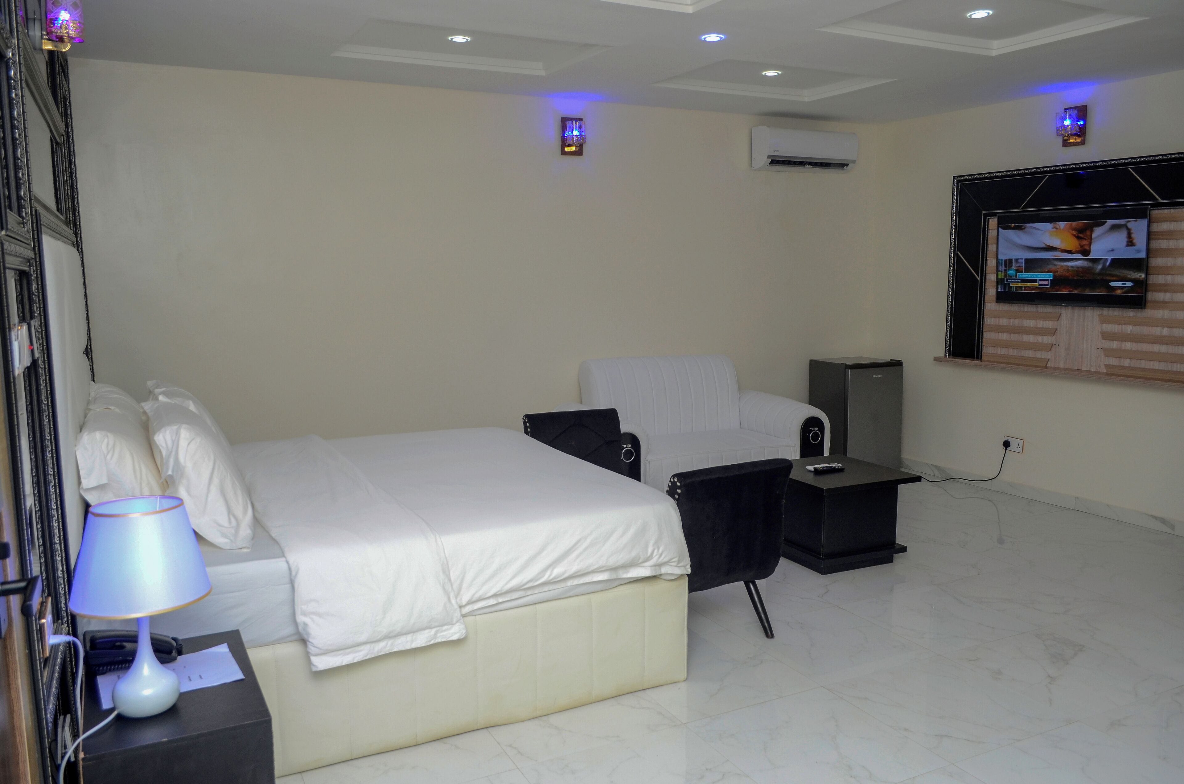 Habitación de hotel con cama, escritorio, silla, televisor y aire acondicionado.