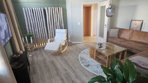 Un saló modern amb una cadira blanca, una taula de centre de fusta i una planta gran.