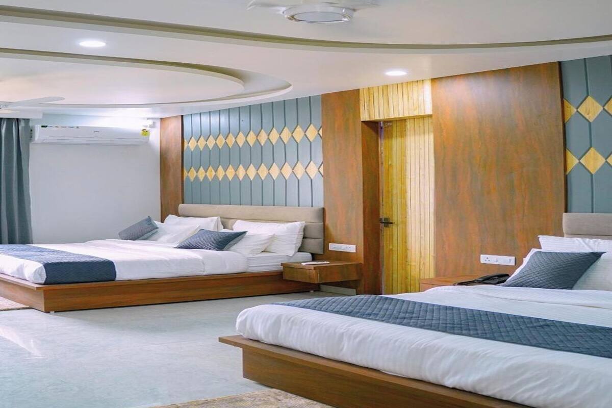 Habitación de hotel con dos camas, cabecero de madera, pared estampada y ventilador de techo.