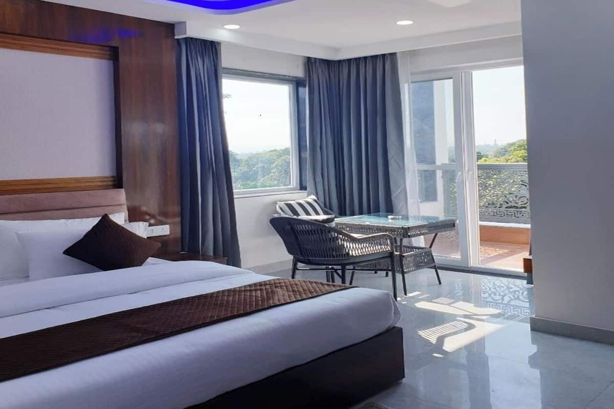 Habitación de hotel moderna con una cama grande, una mesa de comedor y un balcón con vistas.