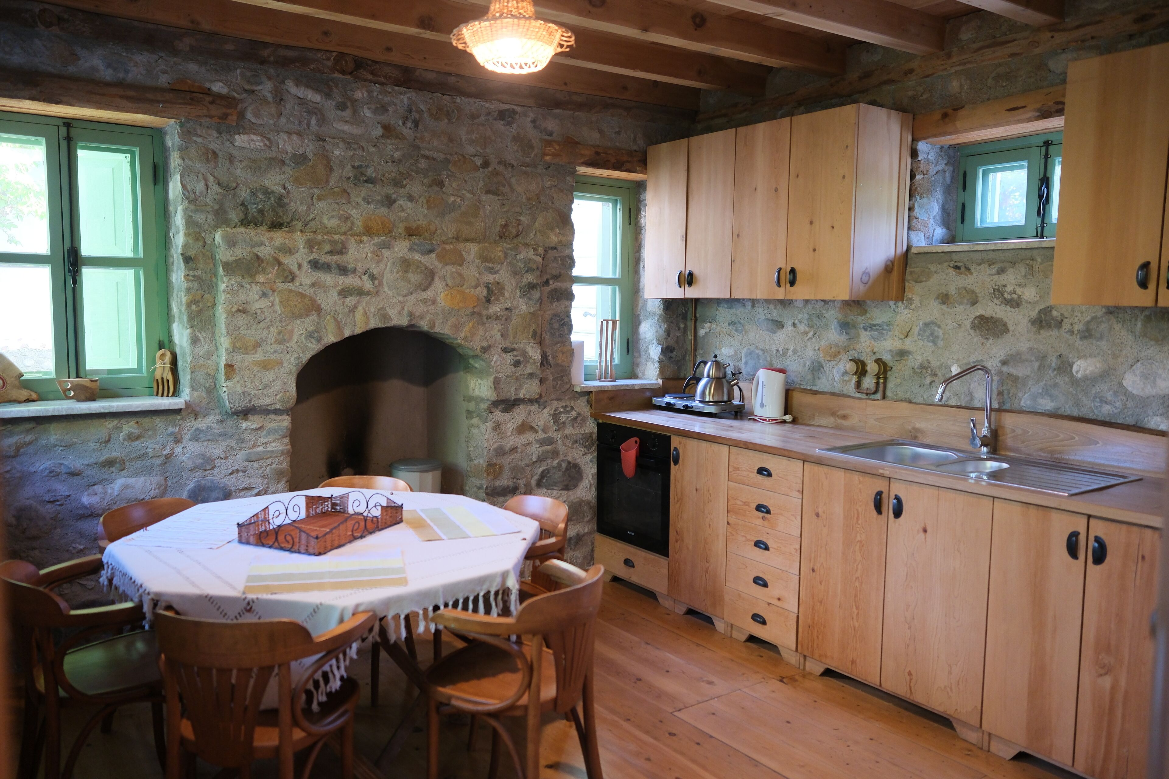 Une cuisine rustique avec des murs en pierre, des armoires en bois, une table à manger avec des chaises et un four encastré.