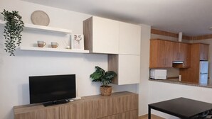 A modern kitchen with wooden cabinets, a built-in microwave, and a dining area with a table and chairs. - Casa cañaveral     . (Conil de la Frontera)