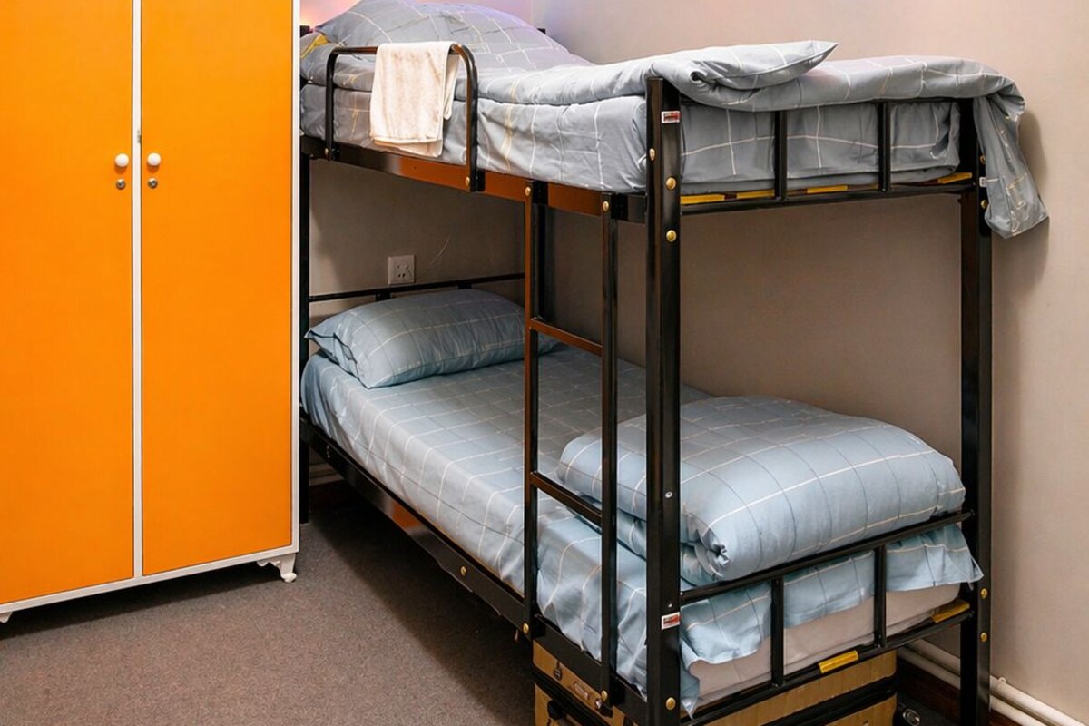 Una cama litera con un armario y una guirnalda de luces de colores.