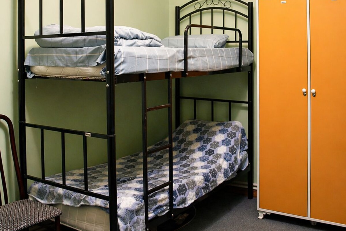 A bunk bed with a chair and an orange wardrobe in a room with green walls.