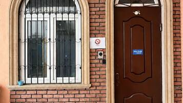 A hotel entrance with a brown door, a welcome mat, and a no smoking sign.