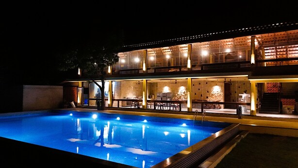 Ein zweistöckiges Gebäude mit einem Pool im Vordergrund. Es hat große Glasfenster und eine Ziegel-Fassade.