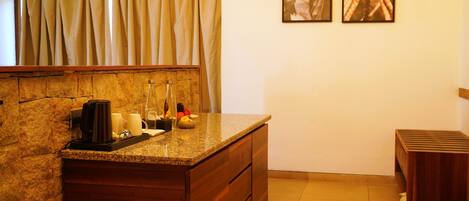 A bathroom with a granite countertop, a coffee maker, and a bottle of hand soap.
