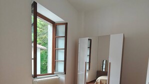 Une chambre avec un grand lit, une armoire, un radiateur et une fenêtre.