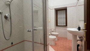 Une salle de bain avec une douche à parois de verre, des toilettes et un lavabo.