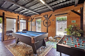 A pool table, foosball table, and a billiards cue rack in a wooden room with large windows and a rustic ceiling. - Luxury Holiday Home with Sauna, Fireplace, Pool Table, Garden, BBQ & Plenty of Space to Relax (Klein Rönnau)