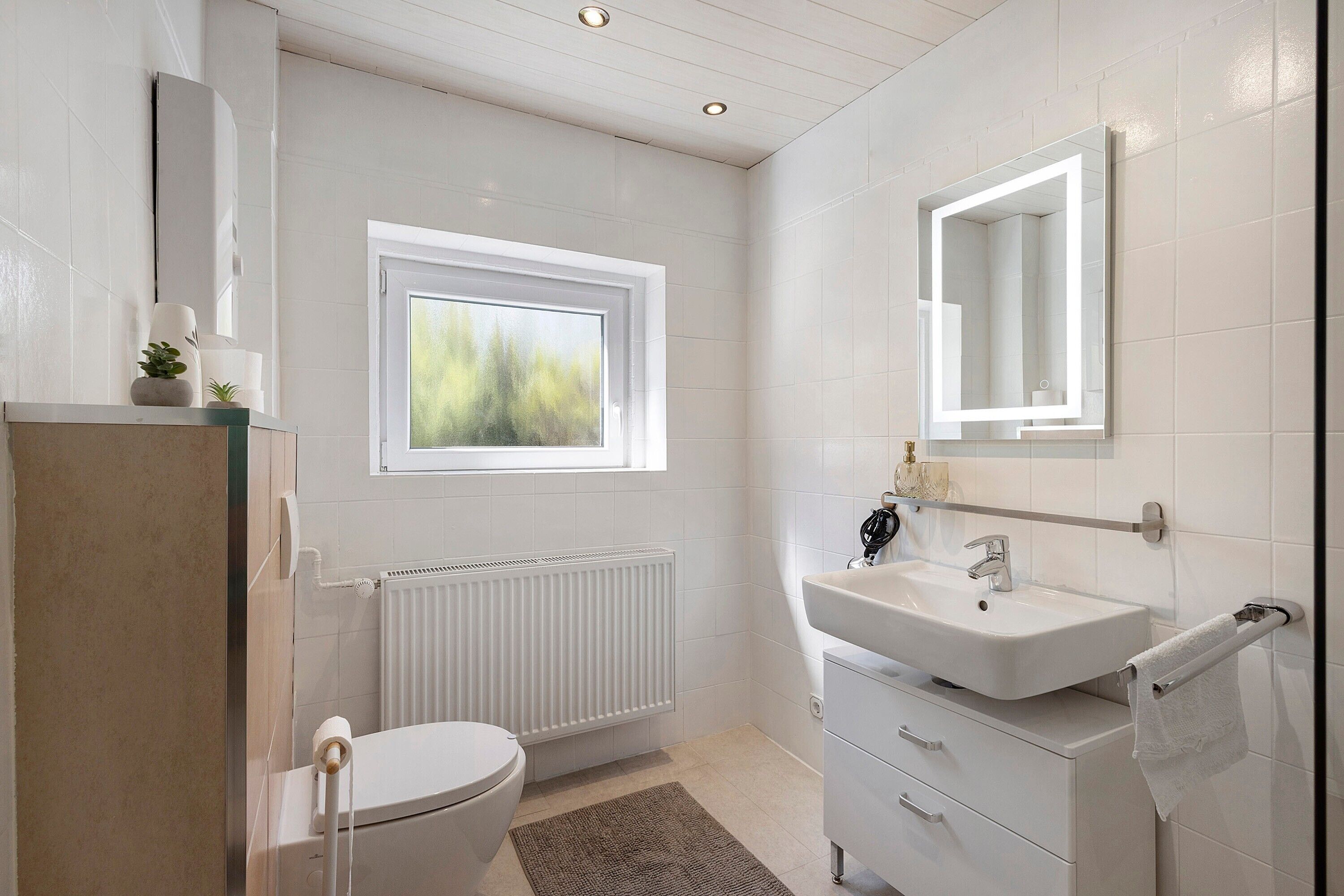 Ein modernes Badezimmer mit Toilette, Waschbecken und Fenster.