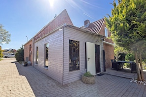 A small, single-story house with a brick chimney, a wooden exterior, and a paved driveway. - Luxury Holiday Home with Sauna, Fireplace, Pool Table, Garden, BBQ & Plenty of Space to Relax (Klein Rönnau)