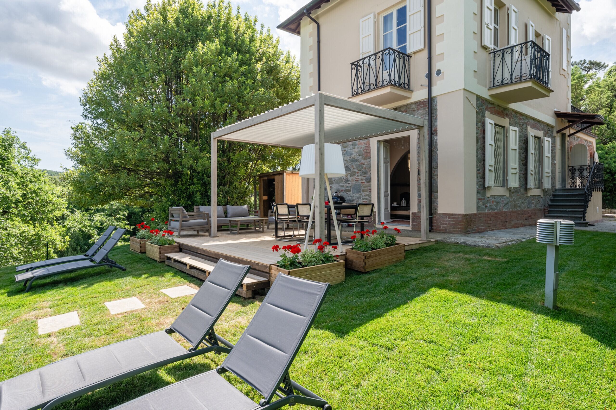 A two-story house with a covered patio, outdoor furniture, and a garden.