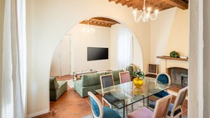 Uma sala de estar com uma mesa de vidro, sofá verde e lareira.