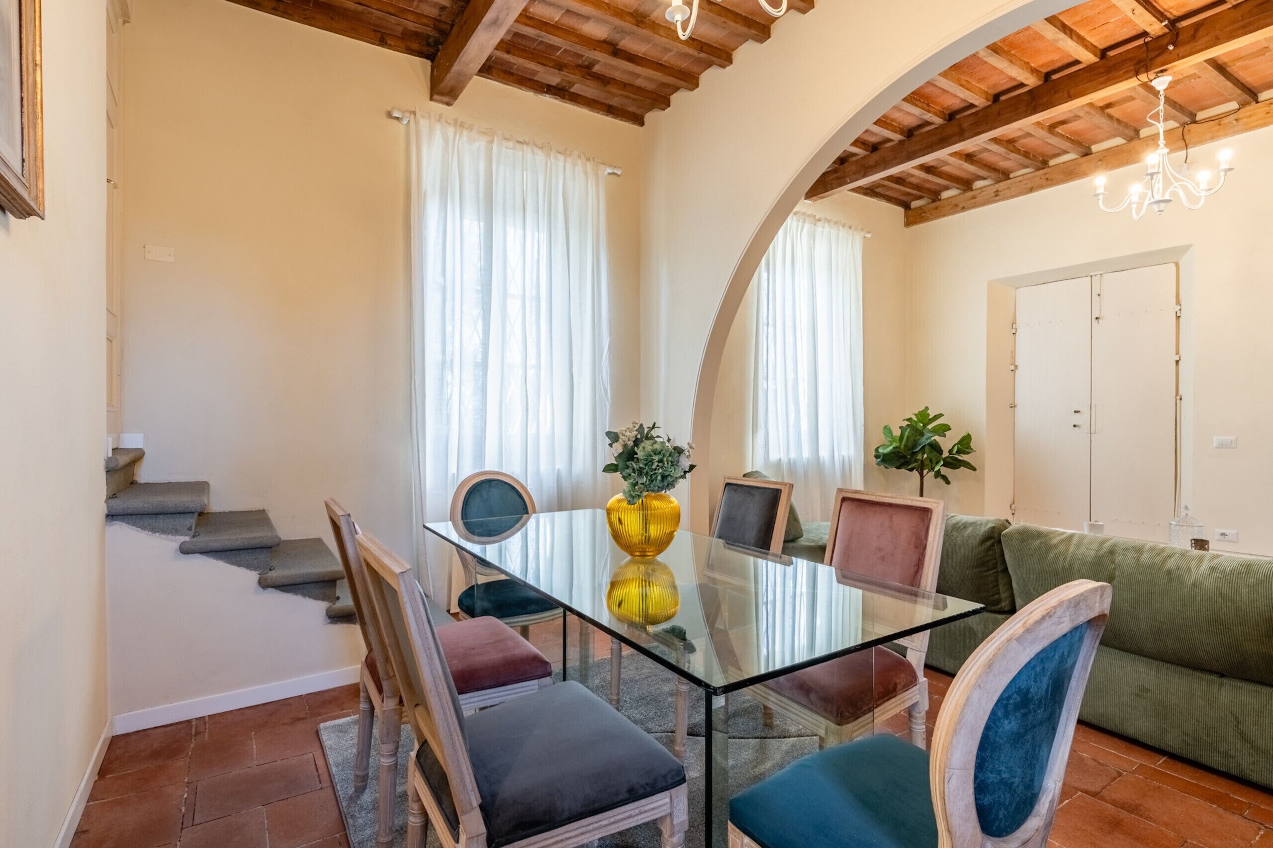 A dining area with a glass table, chairs, and a sofa.