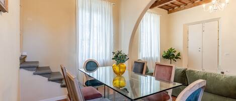 A dining area with a glass table, chairs, and a sofa.
