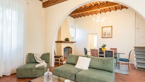 Uma sala de estar aconchegante com um sofá verde, uma mesa de centro de vidro e uma lareira.