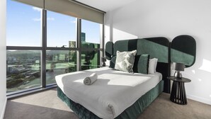 Quarto moderno com uma cama grande, vista para a cidade e um ventilador de teto.