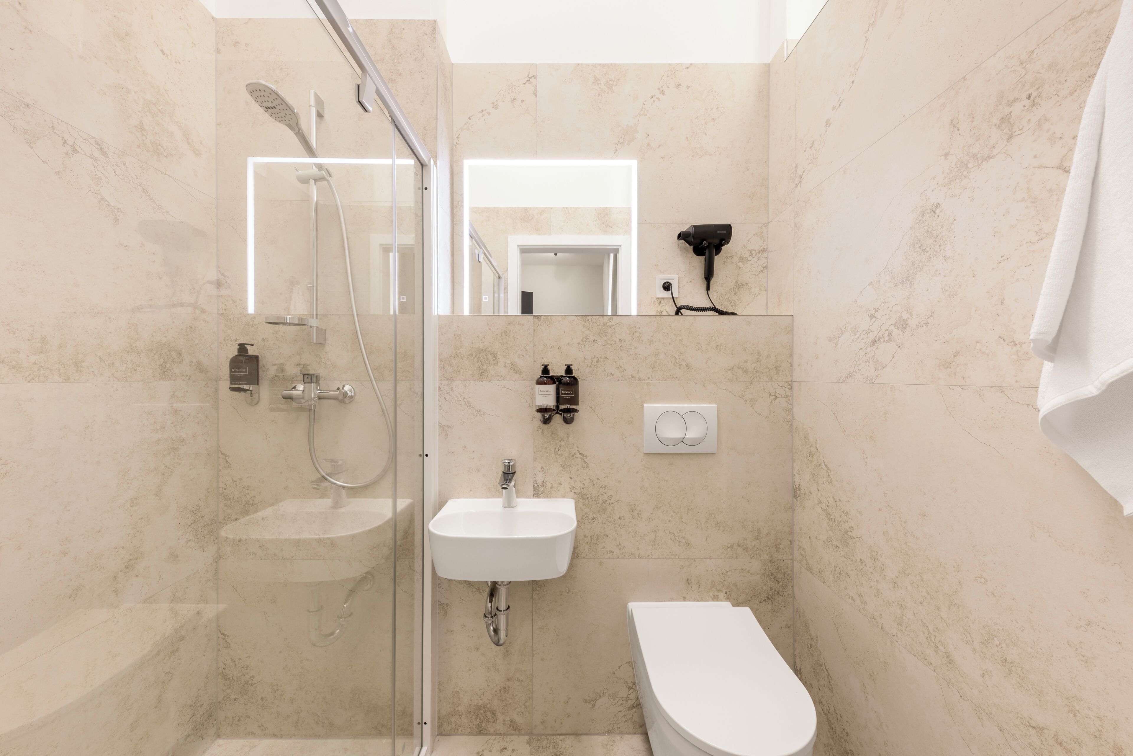 Un baño moderno con ducha envuelta en cristal, un lavabo blanco y un inodoro.