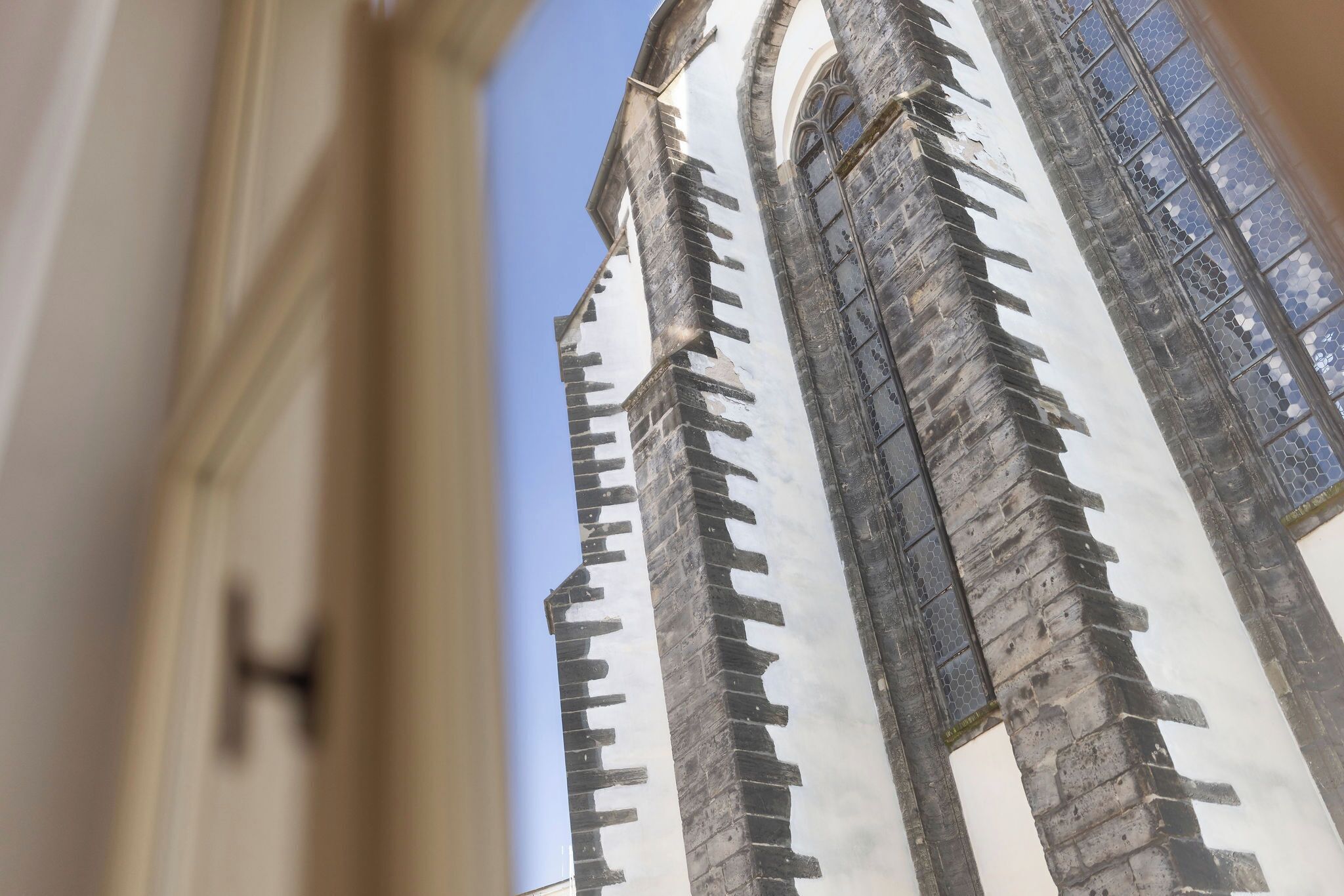 A view of a tall, narrow building with a pointed roof and a series of windows.