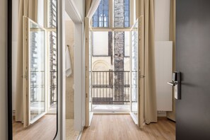 An open doorway leading to a balcony with a view of a building with a brick facade and a metal railing. - Youngmann House (Prague)