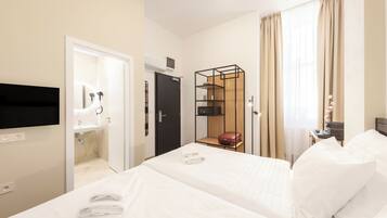 Habitación de hotel con dos camas, baño, televisor y armario.
