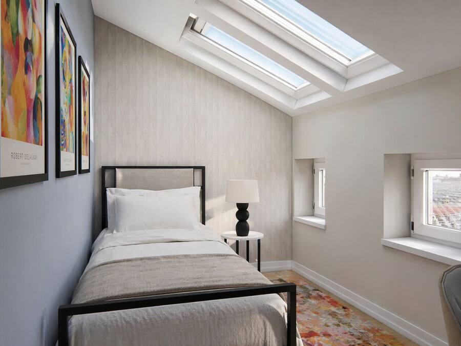 Un dormitorio con tragaluz, cama, mesita de noche, silla y ventana con vistas.