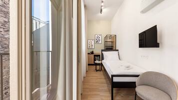 Une chambre à coucher moderne avec un lit, une chaise, un téléviseur et une armoire.