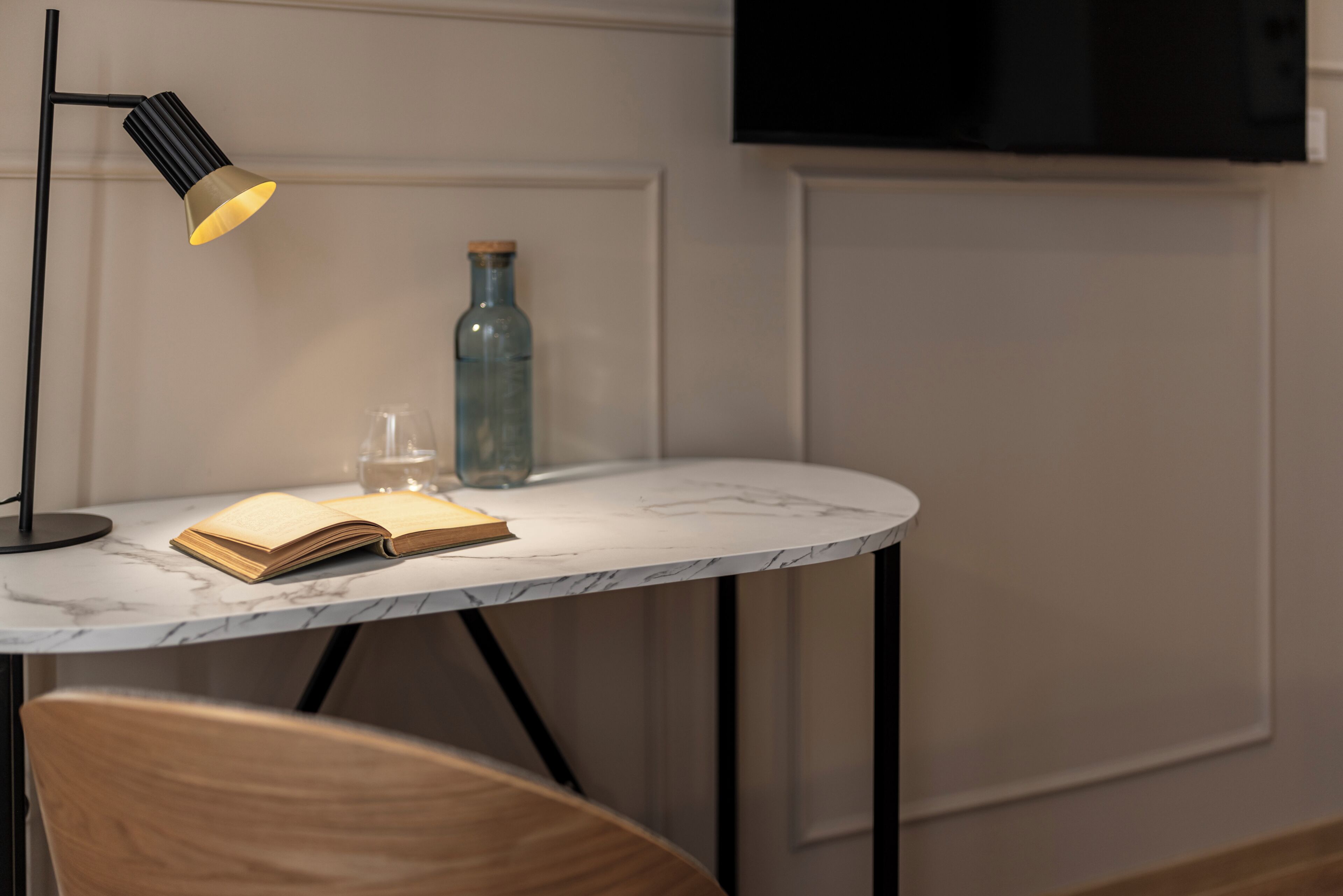 Una mesa con cubierta de mármol, un libro, un vaso y una botella.
