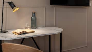 Una mesa con cubierta de mármol, un libro, un vaso y una botella.