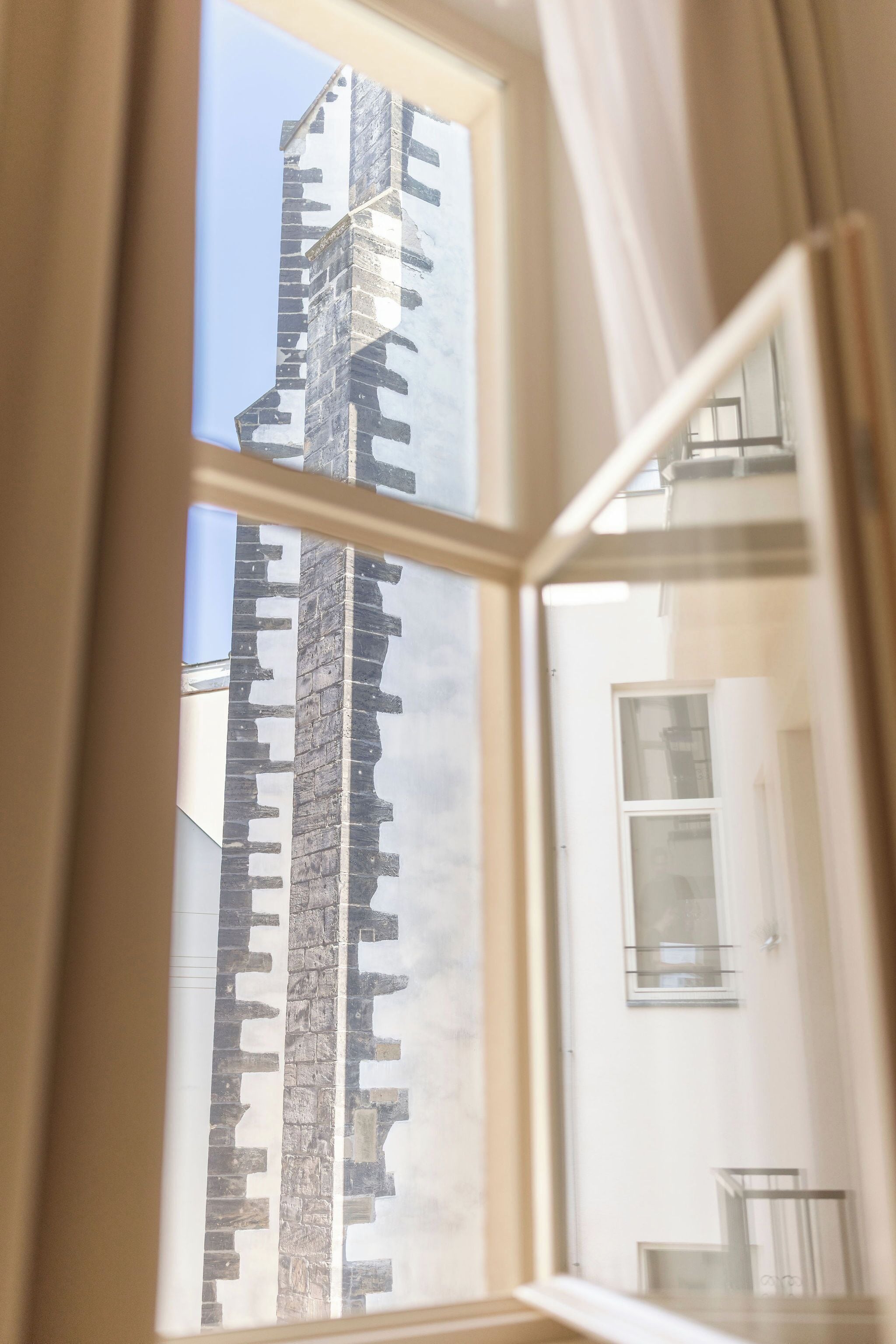 Ventana con vista del exterior de un edificio, que incluye una esquina y parte de una pared.