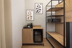 A compact kitchenette with a coffee maker, tea set, and a microwave. There are two framed abstract paintings on the wall. - Youngmann House (Prague)