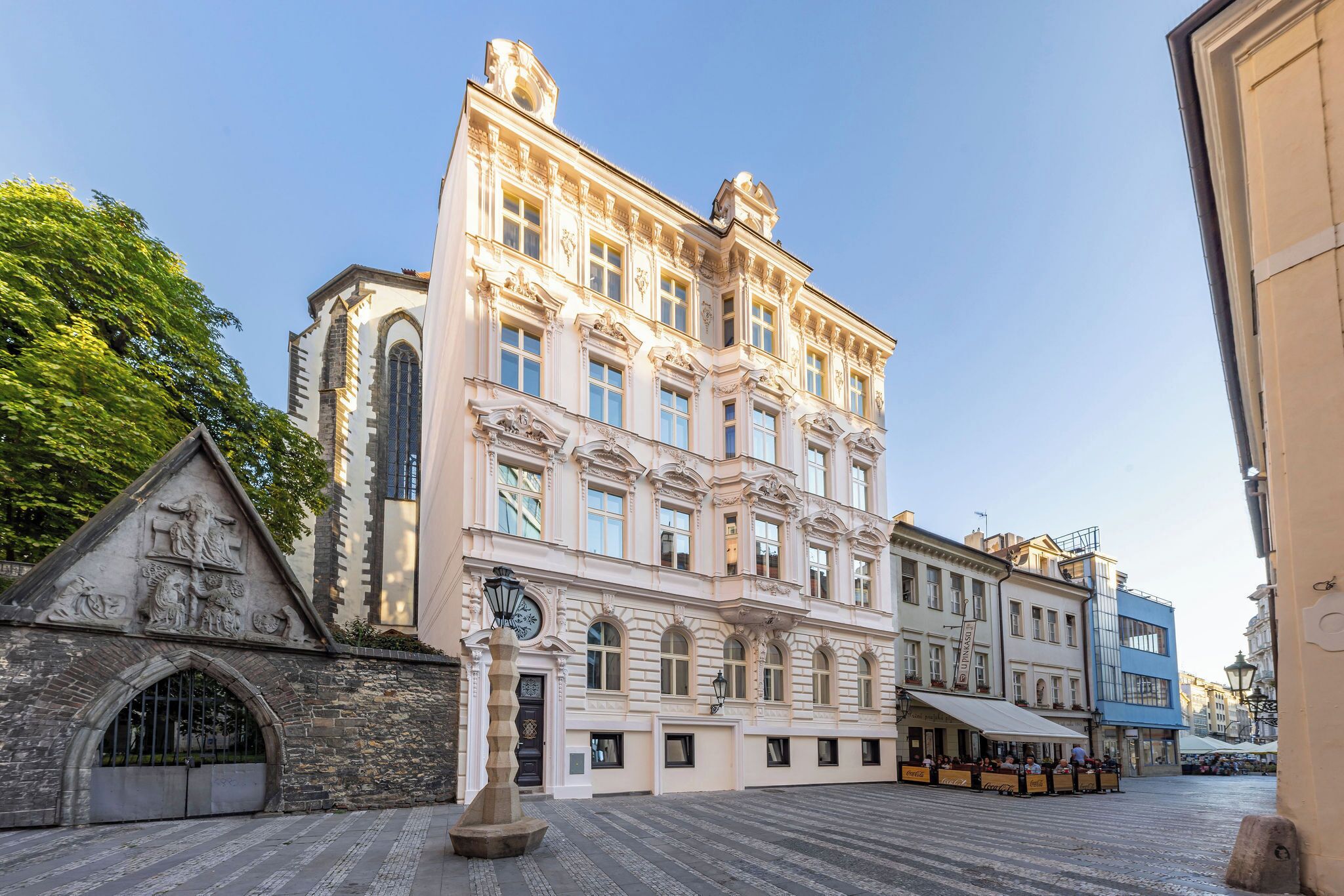 A historic building with classical architecture, a cobblestone street, and a café with outdoor seating.