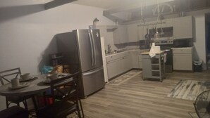 A compact kitchen with a refrigerator, microwave, and sink. There is a dining table with chairs and a rug. - Nice 1-bedroom cottage with AC in charming West Liberty (West Liberty)