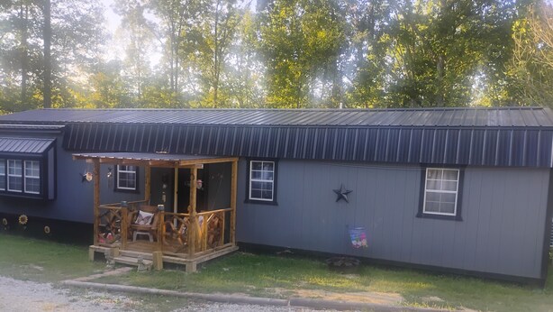A rustic cabin with a porch, a star decoration, and a small window. - Nice 1-bedroom cottage with AC in charming West Liberty (West Liberty)