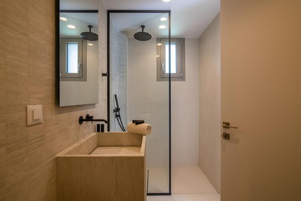 Un bagno moderno con un mobile vanitario in legno, box doccia in vetro e uno specchio grande.