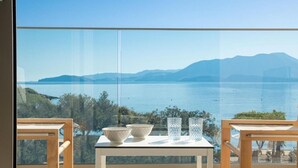 Un balcón con una mesa, dos sillas y vistas a un lago y montañas.