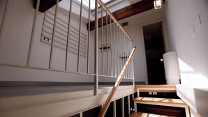 A staircase with wooden steps and a white railing, leading to a room with a skylight and a door. - Ponte Vecchio SPA & Lift (Firenze)
