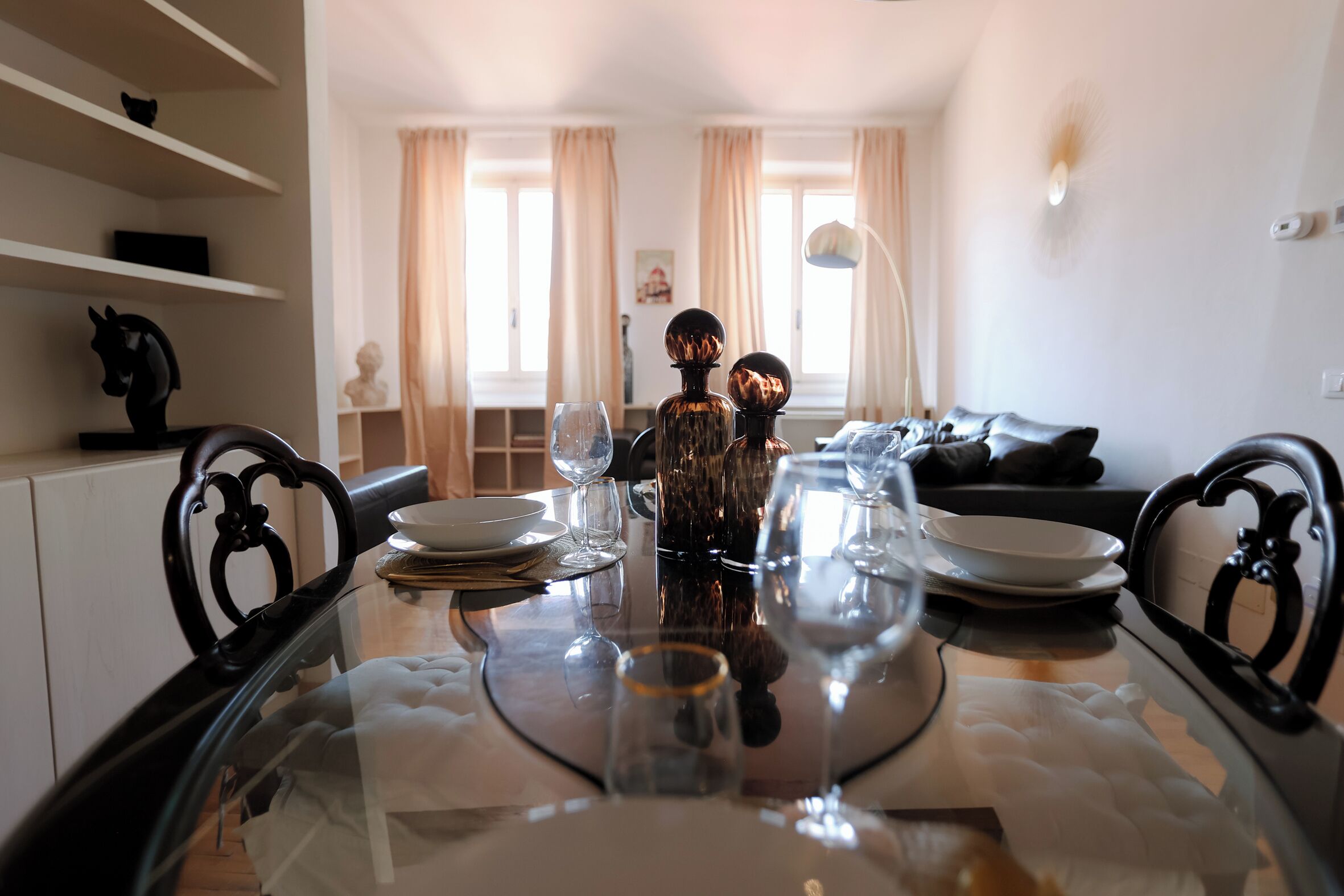 Une table à manger dressée avec des assiettes, des verres et une bouteille décorative.