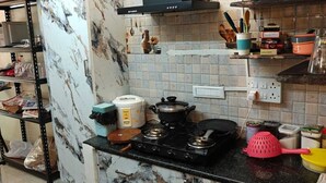 Eine Küche mit Marmorfliesenspiegel, einem Gasherd, einem Reiskocher und verschiedenen Küchenutensilien.