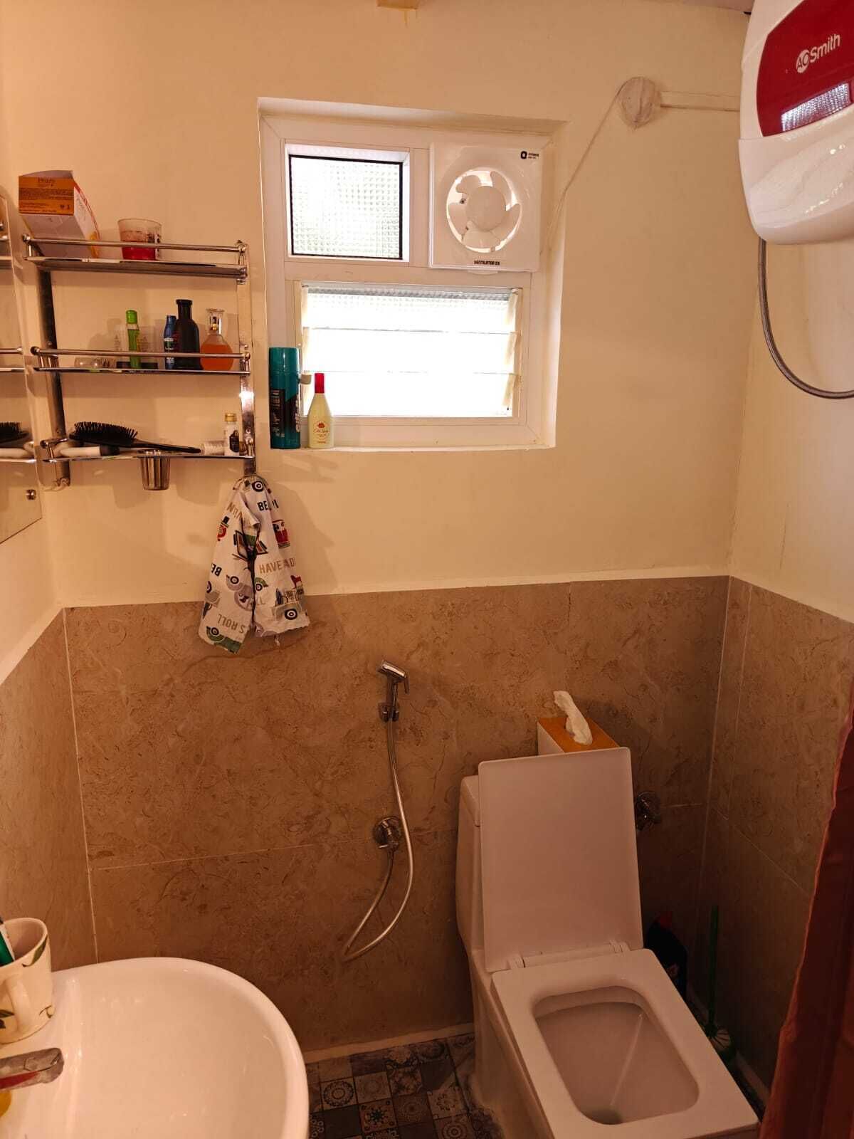 Un baño con ducha, inodoro y ventana con persianas.