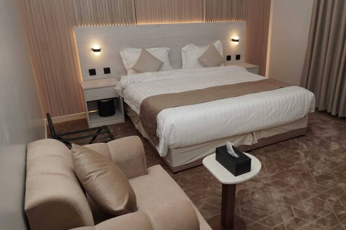 Een hotelkamer met een groot bed, twee nachtkastjes, een bank en een kleintje tafel met een zakdoekendoos.