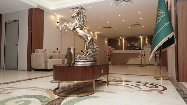 A lobby with a central statue, a reception desk, and a flag.