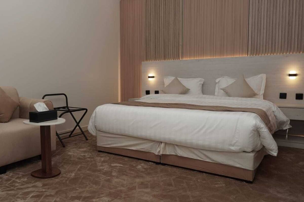 Een moderne hotelkamer met een groot bed, een bank, een klein tafeltje en een stoel.