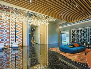 A modern lobby with a reflective floor, a blue sofa, and a patterned wall. - KL Majestic VIP Studio Massage Chair 26-1a Klcc View (Kuala Lumpur)