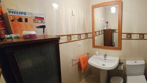 Une salle de bain avec un lavabo, des toilettes et un miroir. Il y a une publicité pour la marque Philips sur le mur.