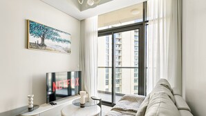 Ein modernes Wohnzimmer mit großem Fenster, Flachbildfernseher, Sofa und einem kleinen Tisch mit einer Dekoration.