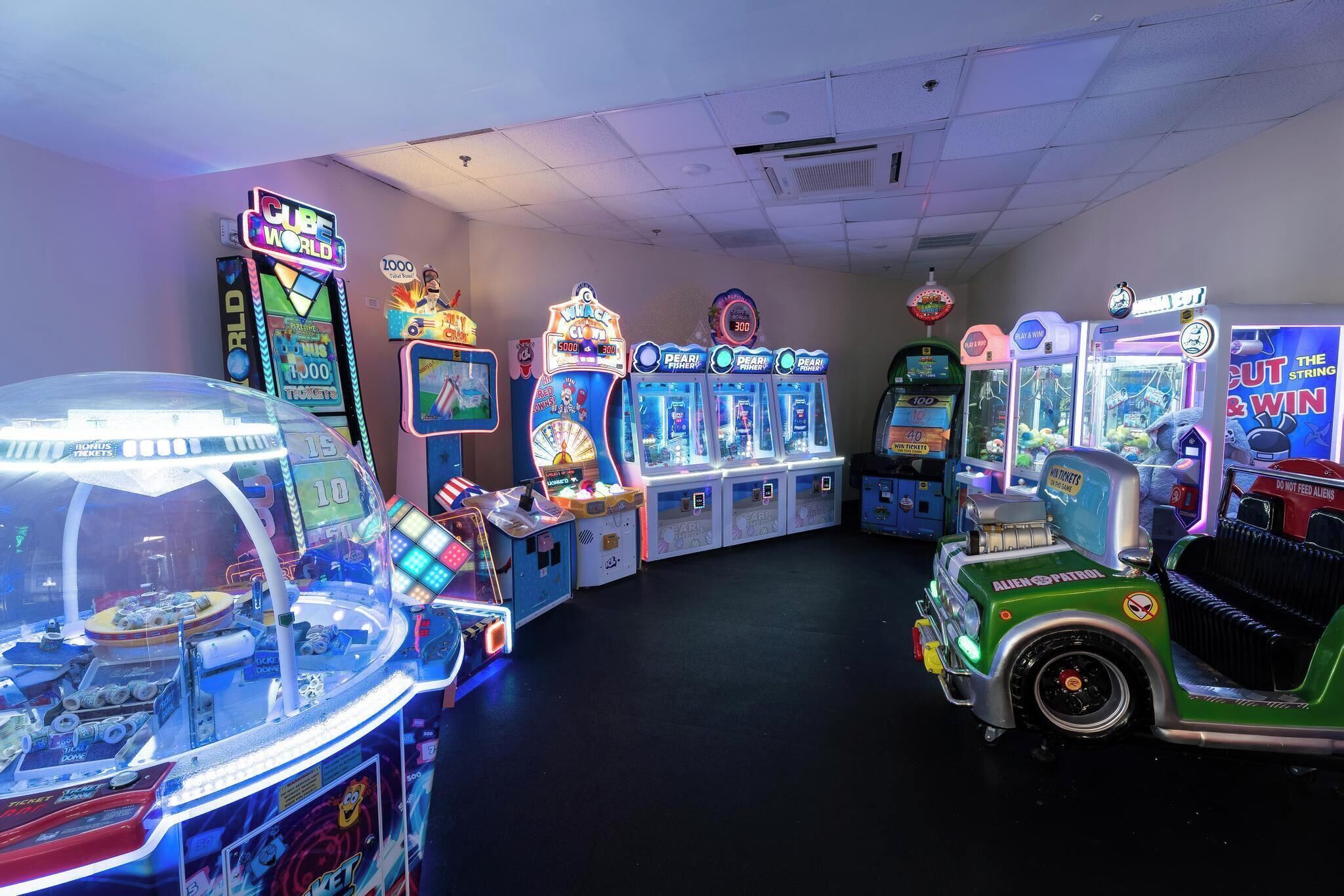 Una hilera de juegos de arcade, incluyendo máquinas de garra y juegos de carreras.
